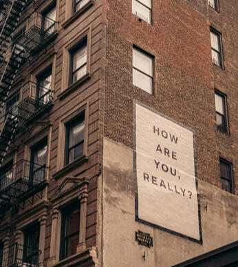 How are you, really? Image of a building with a poster reading 'How are you, really?'